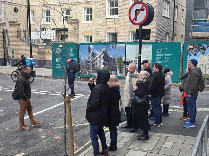 Tour group on a street corner beside construction hoardings
