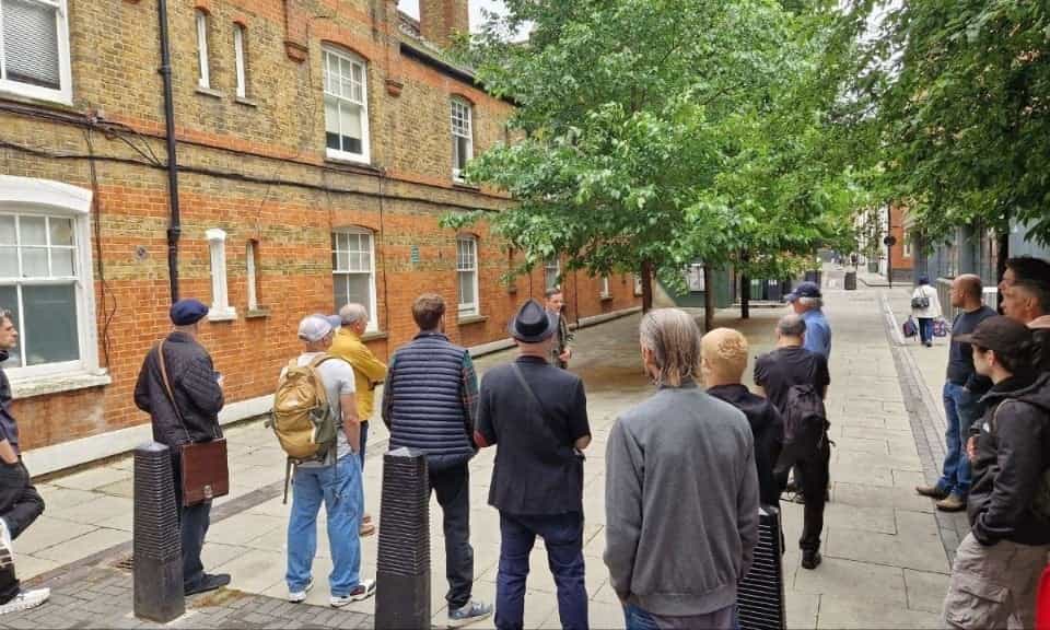 Tour group on a Fleet Street side street listening to the guide beside historic brick buildings
