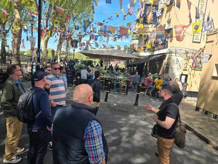 Guide with walkers near Trafalgar Tavern in Greenwich under signal flags